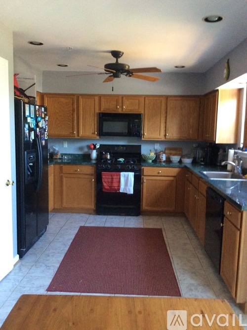 A kitchen with wooden cabinets and a black refrigerator.