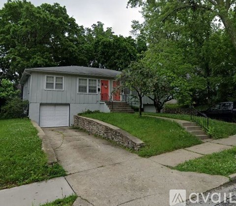 A house with a red door is surrounded by greenery.