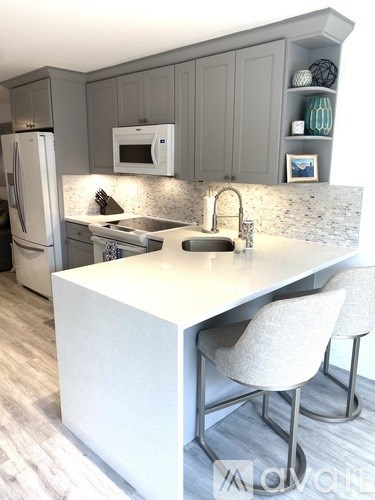 A kitchen with a white island and grey cabinets.