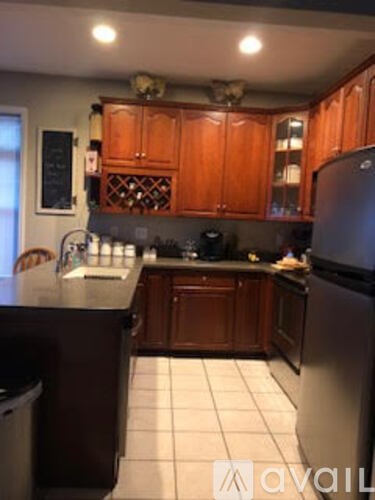 A kitchen with wooden cabinets and a black fridge.