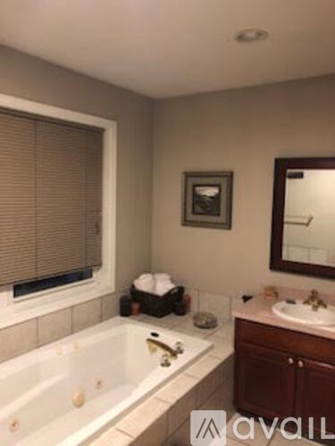 A bathroom with a tub, sink, and mirror.