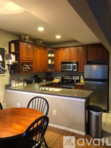 A kitchen with wooden cabinets and a table with chairs.