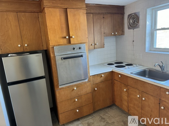 A kitchen with wooden cabinets and a stainless steel refrigerator.
