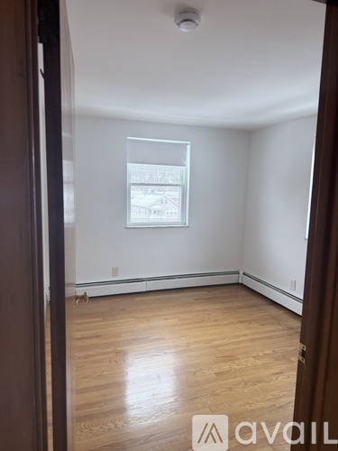 A room with wooden floors and a white wall with a window.
