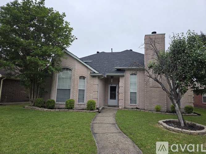A house with a brick exterior and a tree in front.