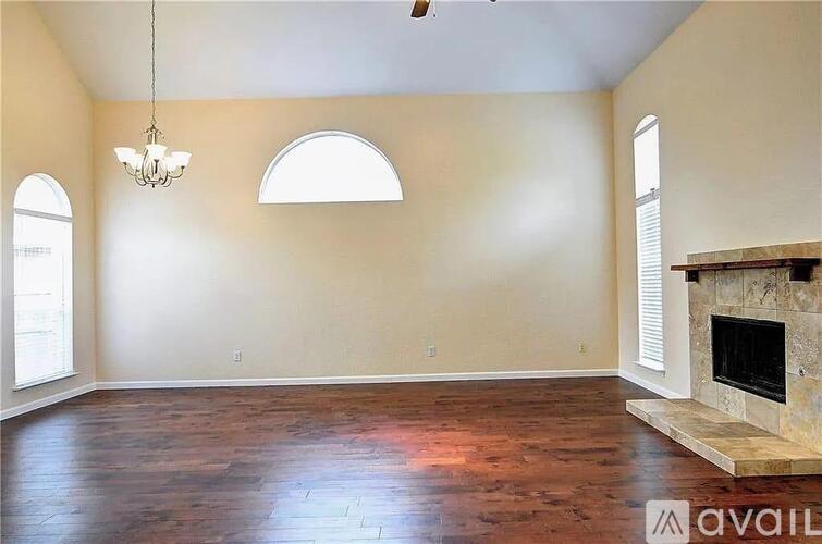 A large empty room with a fireplace and a chandelier.