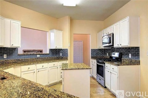 A kitchen with white cabinets and a granite countertop.