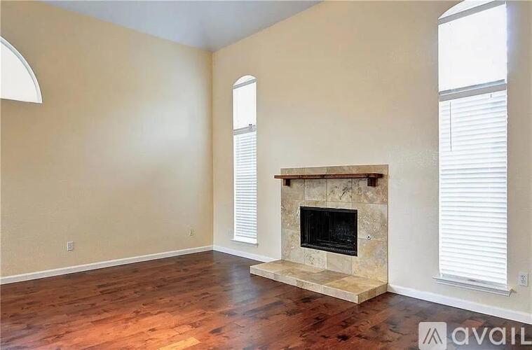 A living room with a fireplace and two windows.