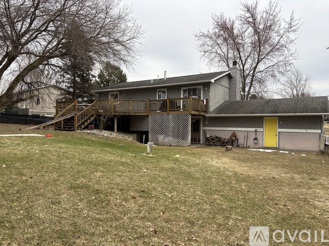 A house with a yellow door is surrounded by a fence and has a deck.