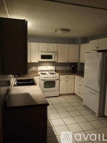 A kitchen with white cabinets and appliances.