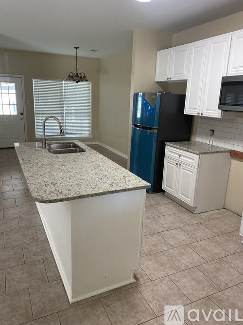 A kitchen with a granite countertop and a blue refrigerator.