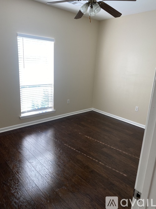A room with a ceiling fan and wooden flooring.