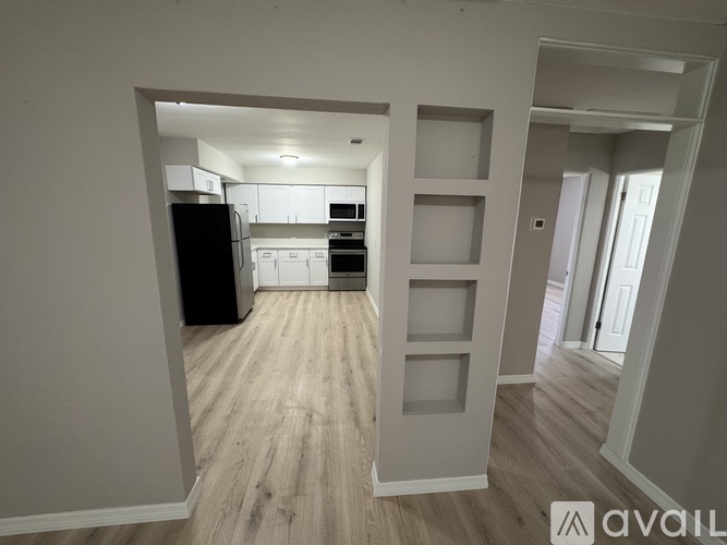 A kitchen with a black refrigerator and white cabinets is visible through a doorway.
