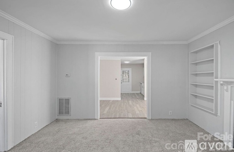 A room with a carpet floor and a doorway leading to another room.