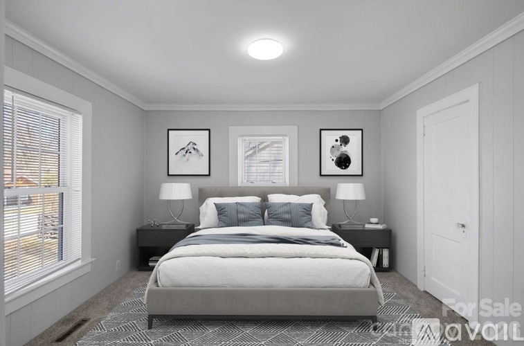 A bedroom with a bed, two lamps, and pictures on the wall.
