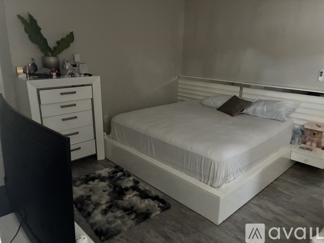 A bedroom with a bed, nightstand, and a TV.