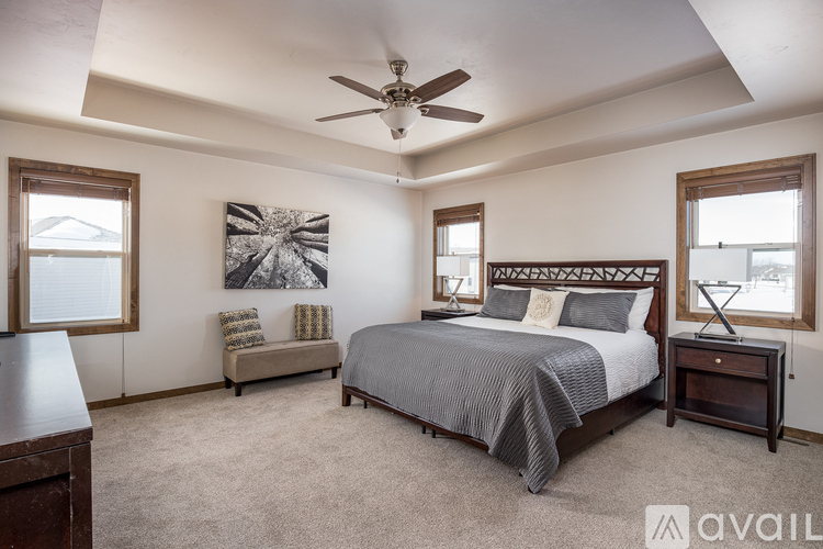 A bedroom with a large bed, a bench, and a ceiling fan.