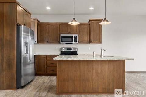 A kitchen with wooden cabinets and a stainless steel refrigerator.