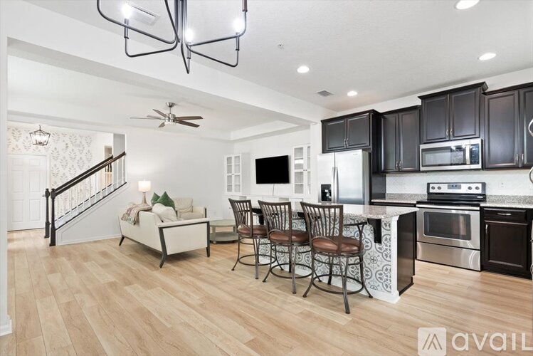 A kitchen with black cabinets and a wooden floor.