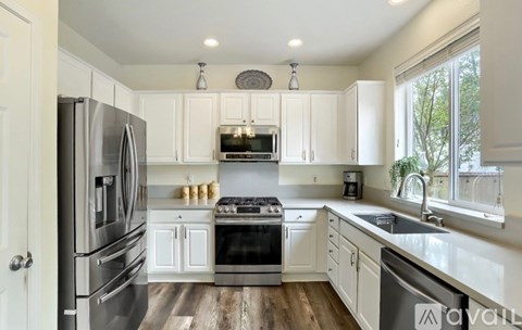 A modern kitchen with white cabinets and stainless steel appliances.