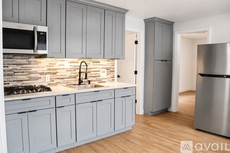 A kitchen with grey cabinets and a stainless steel refrigerator.