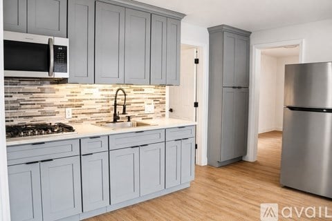 A kitchen with grey cabinets and a stainless steel refrigerator.