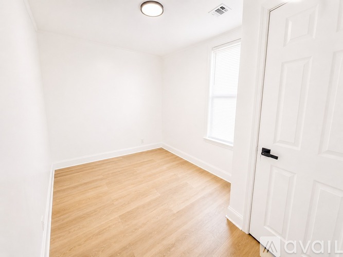 A room with a white door and wooden floor.