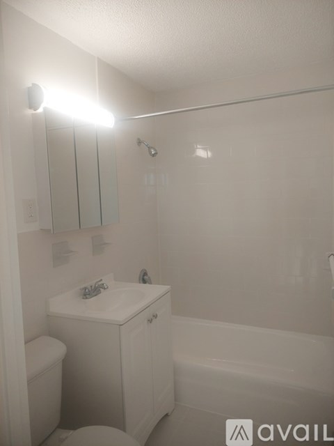 A white bathroom with a toilet, sink, and mirror.
