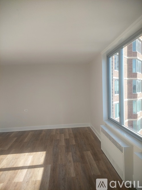 A room with wooden floors and a window overlooking a brick building.