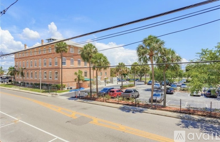 A street view of a red brick building with cars parked in front.