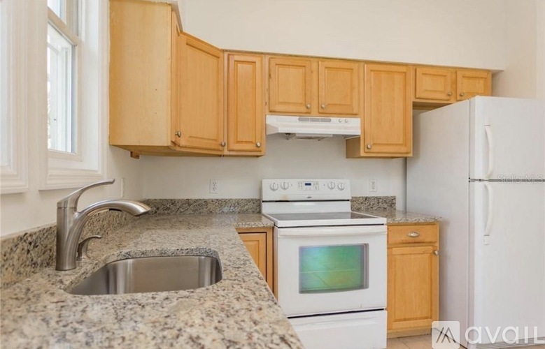A kitchen with a granite countertop and wooden cabinets.