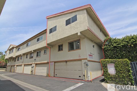 A two-story building with a red roof and a garage door.