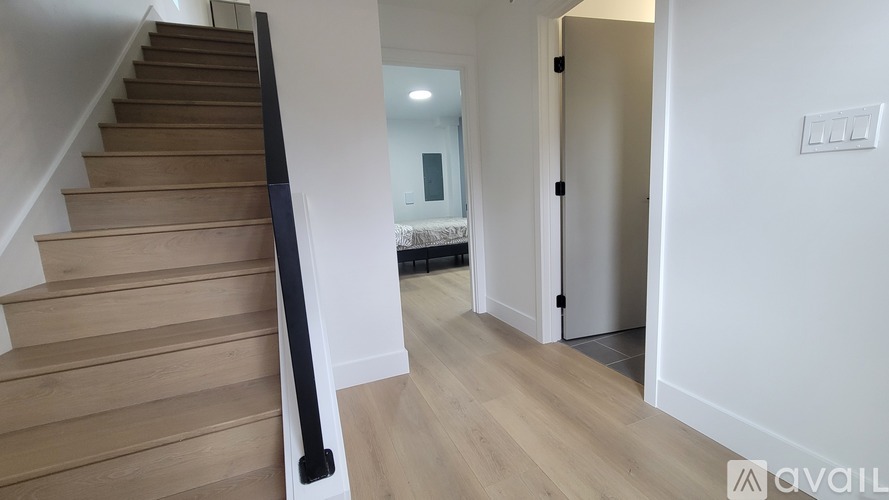 A hallway with a staircase on the left and a door on the right.