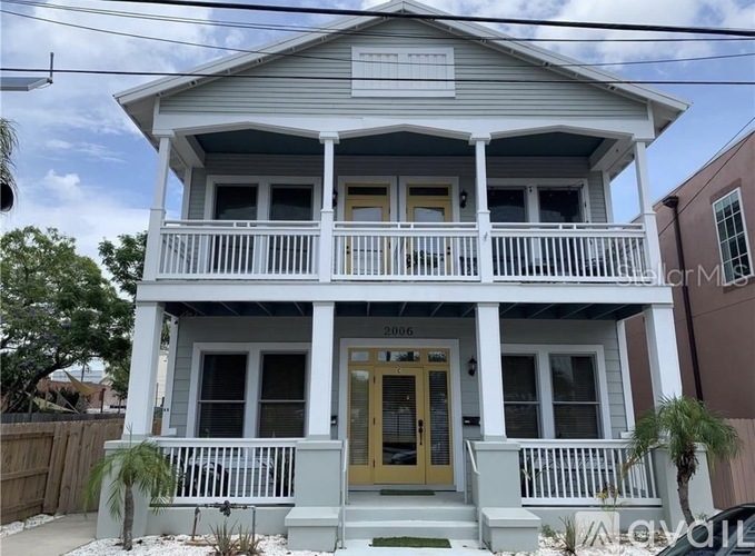 A two-story house with a yellow front door and white railings.