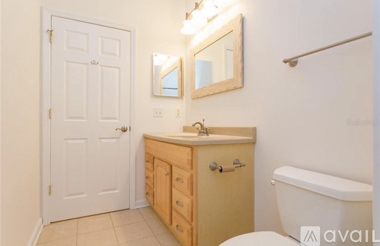 A bathroom with a white door, a wooden cabinet, a white sink, and a white bathtub.
