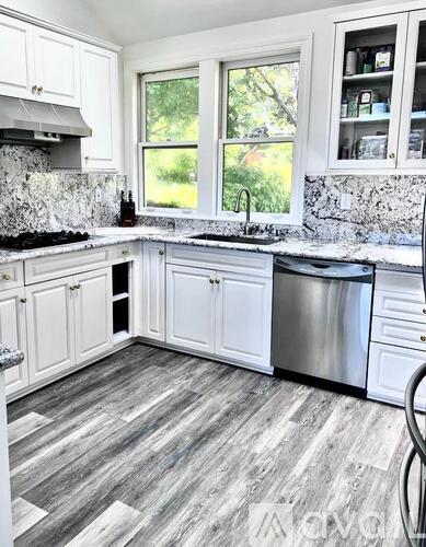 A kitchen with white cabinets and a grey floor.