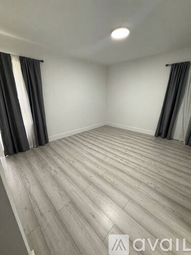 A room with wooden flooring and grey curtains.