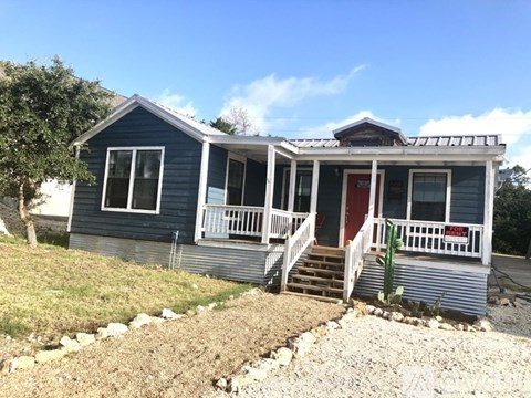 A blue house with a red door and white railings.