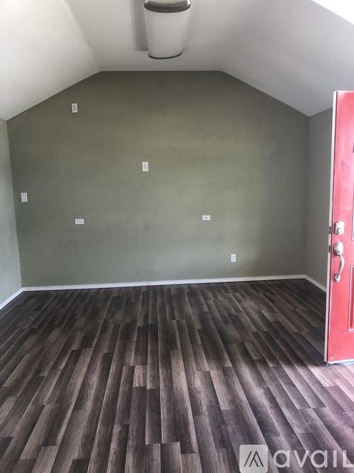 A room with a wooden floor and a red door.