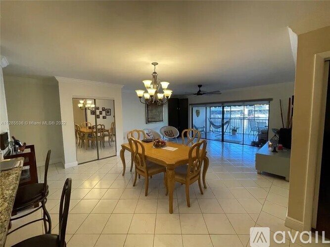 A dining room with a table set for six and a chandelier hanging from the ceiling.