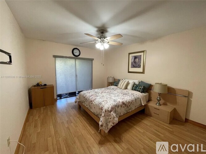 A bedroom with a bed, nightstand, and a ceiling fan.