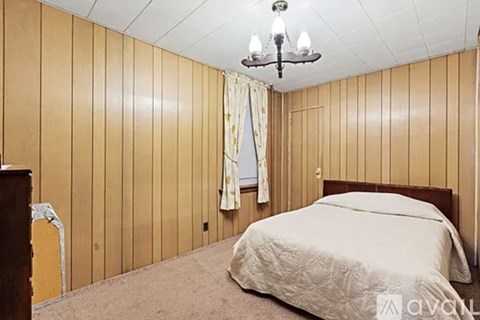 A bedroom with a bed, wooden headboard, and a chandelier.