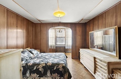 A bedroom with a floral bedspread and a large mirror on the dresser.