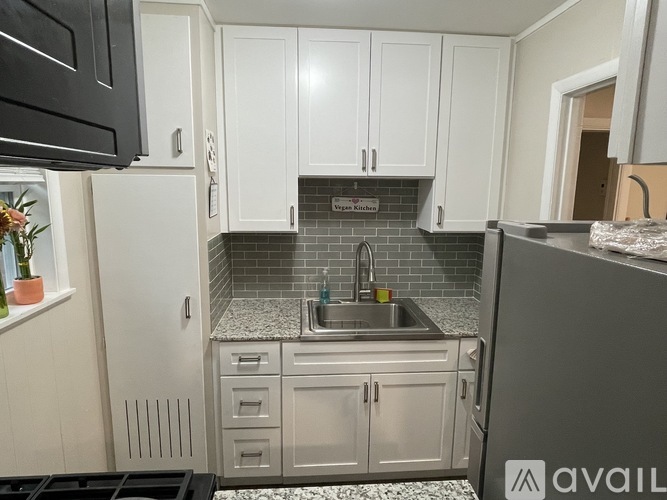 A kitchen with white cabinets and a black microwave.