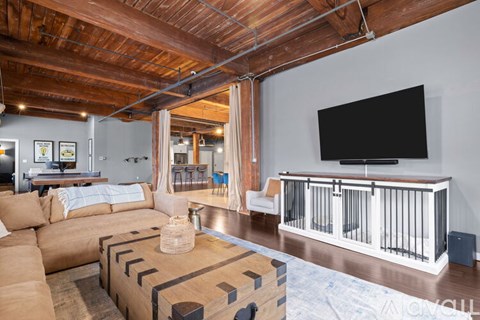 A living room with a brown sofa and a television on the wall.