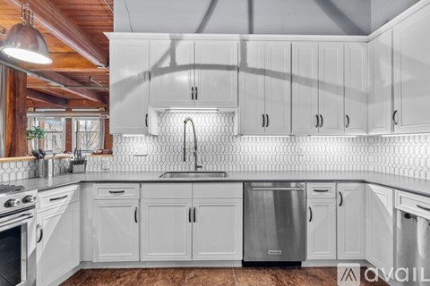 A kitchen with white cabinets and a wooden ceiling.