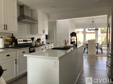 A kitchen with white cabinets and a marble countertop.