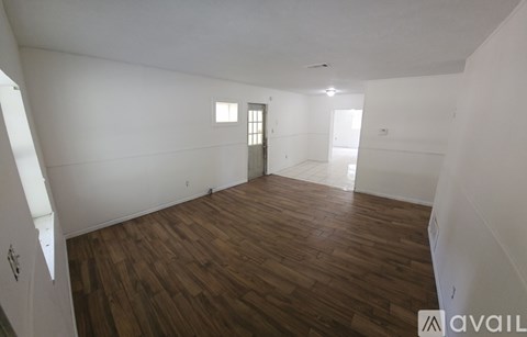 A room with wooden flooring and white walls.