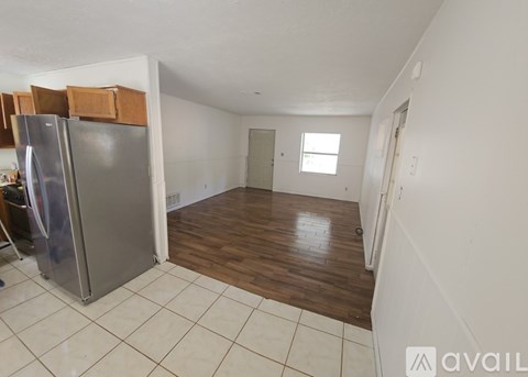A kitchen with a refrigerator and wooden floors.