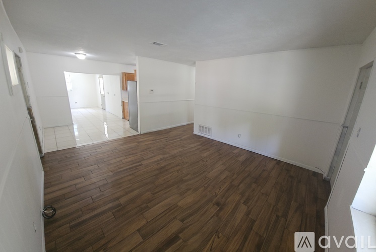 A room with wooden flooring and white walls.